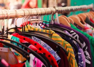 Close-up photograph of multi-coloured clothing hanging on a clothes rail.