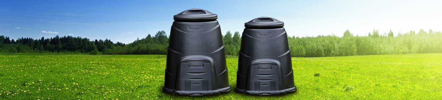 Two black plastic compost bins in a sunny meadow.