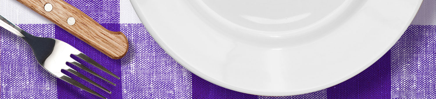 White dinner plate, with knife and fork on a purple checked table cloth